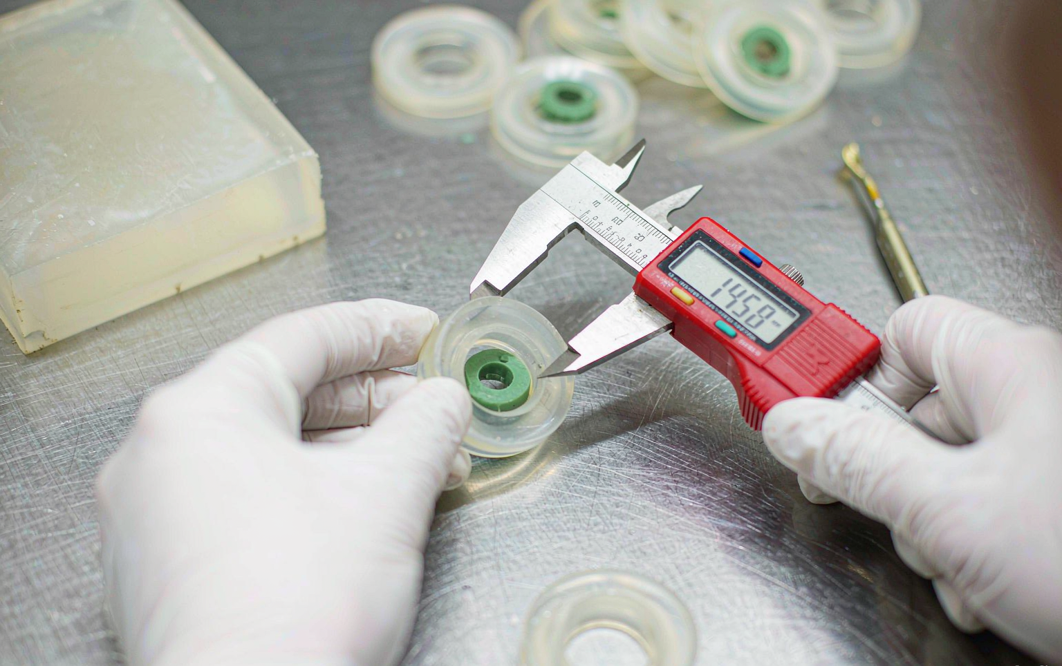 Quality inspector measuring freshly molded silicone parts with calipers